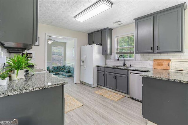 3589 Garden Manor Dr, Loganville, GA 30052 - kitchen with white refrigerator with ice dispenser, gray cabinetry, light wood-style flooring, a textured ceiling, and light stone counters