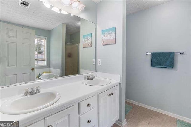 3589 Garden Manor Dr, Loganville, GA 30052 - bathroom featuring a textured ceiling, double vanity, a shower with shower door, and tile patterned floors