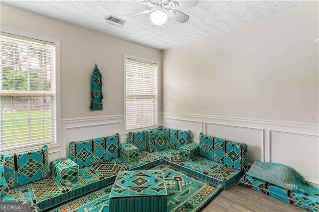 3589 Garden Manor Dr, Loganville, GA 30052 - living room with ceiling fan, a textured ceiling, a decorative wall, a wainscoted wall, and wood finished floors