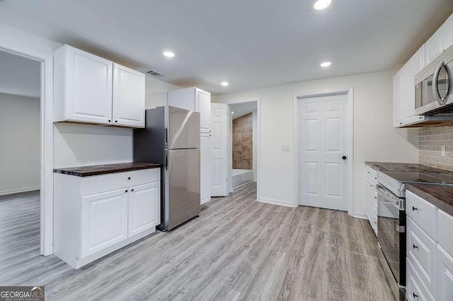 5215 Cordell St, Savannah, GA 31405 - kitchen featuring stainless steel appliances, dark countertops, light wood-style flooring, white cabinetry, and recessed lighting