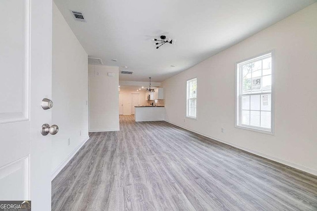5215 Cordell St, Savannah, GA 31405 - unfurnished living room with light wood-style floors and a chandelier