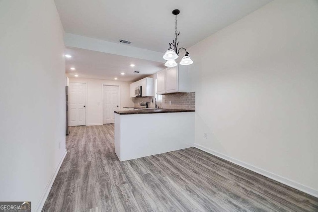 5215 Cordell St, Savannah, GA 31405 - kitchen with dark countertops, wood finished floors, white cabinets, stainless steel appliances, and recessed lighting