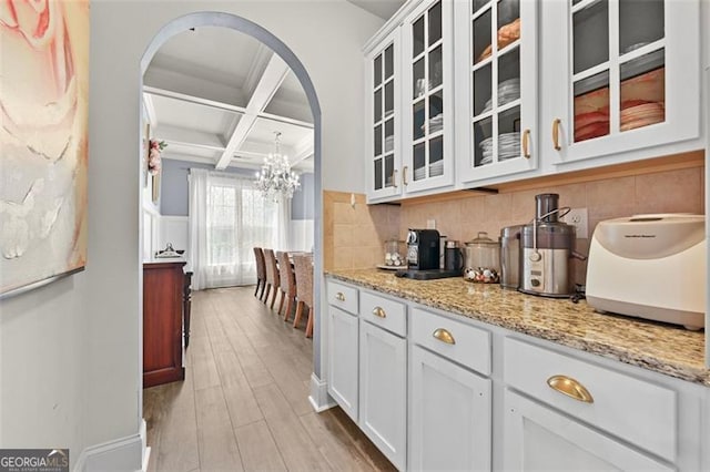 5825 Trailwood Ct, Suwanee, GA 30024 - kitchen with coffered ceiling, arched walkways, light wood-style floors, light stone countertops, and a chandelier