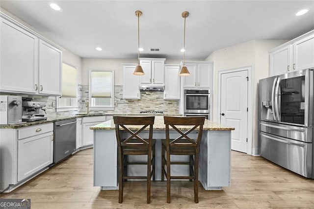 5825 Trailwood Ct, Suwanee, GA 30024 - kitchen with stainless steel appliances, a center island, tasteful backsplash, light stone counters, and light wood-style floors