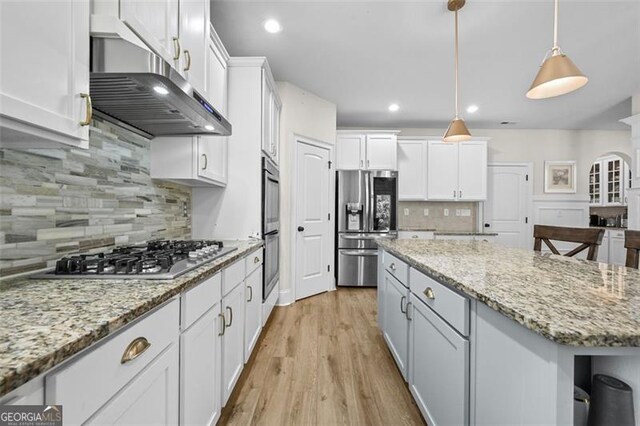 5825 Trailwood Ct, Suwanee, GA 30024 - kitchen with appliances with stainless steel finishes, range hood, a kitchen island, backsplash, and white cabinets