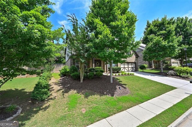 5825 Trailwood Ct, Suwanee, GA 30024 - obstructed view of property featuring concrete driveway, a front lawn, and stone siding