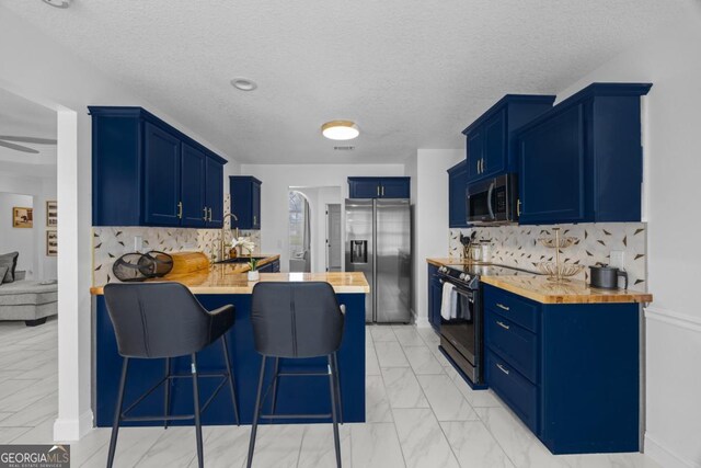 513 Cascade Ct, Hinesville, GA 31313 - kitchen featuring appliances with stainless steel finishes, a peninsula, light marble finish flooring, blue cabinets, and a textured ceiling
