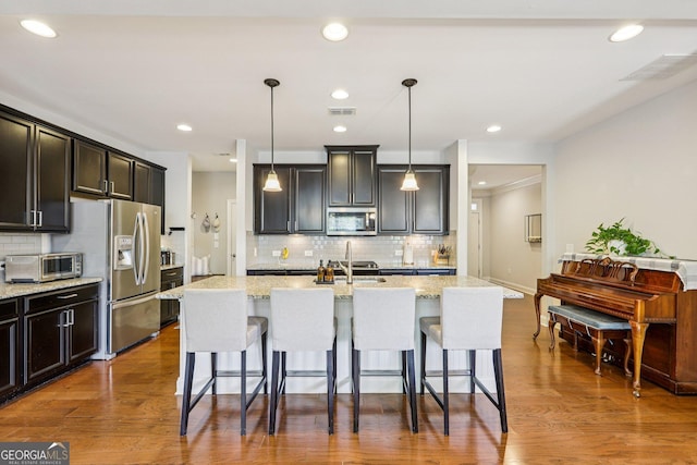 8215 Harlond Way, Suwanee, GA 30024 - kitchen with stainless steel appliances, decorative backsplash, a kitchen bar, a kitchen island with sink, and recessed lighting