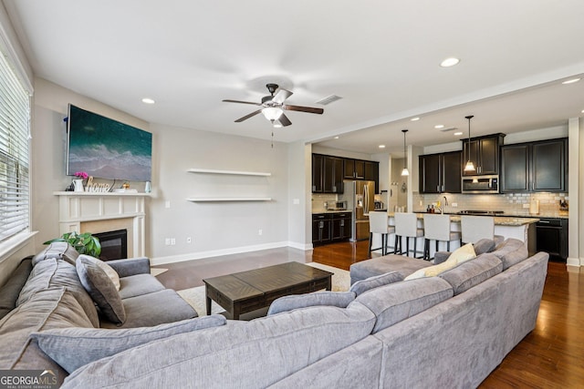 8215 Harlond Way, Suwanee, GA 30024 - living area featuring a glass covered fireplace, ceiling fan, recessed lighting, and dark wood-type flooring