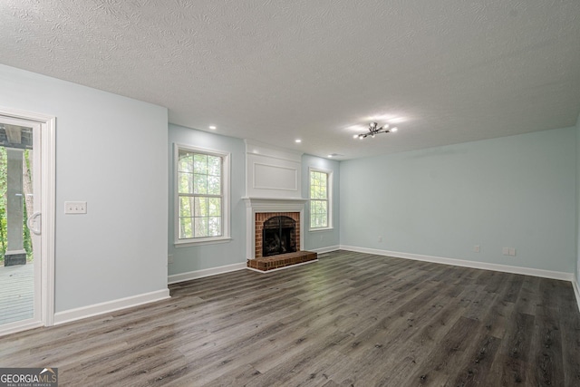 4959 Abbotts Glen Trl NW, Acworth, GA 30101 - unfurnished living room with dark wood-style flooring, a textured ceiling, recessed lighting, and a brick fireplace
