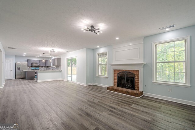 4959 Abbotts Glen Trl NW, Acworth, GA 30101 - unfurnished living room with a textured ceiling, dark wood-style floors, a brick fireplace, and recessed lighting