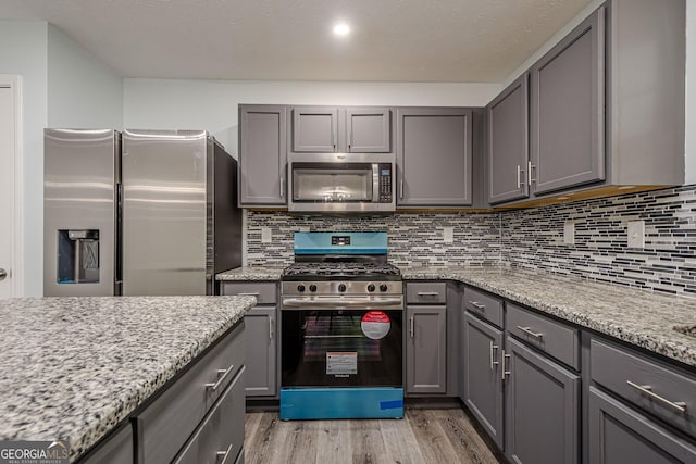 4959 Abbotts Glen Trl NW, Acworth, GA 30101 - kitchen with appliances with stainless steel finishes, gray cabinets, light wood-style flooring, decorative backsplash, and light stone counters