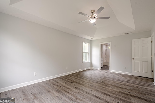4959 Abbotts Glen Trl NW, Acworth, GA 30101 - unfurnished bedroom with a tray ceiling, dark wood-type flooring, connected bathroom, and a ceiling fan