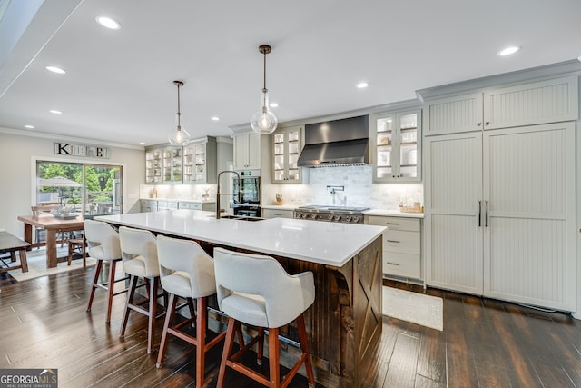 6590 Lights Ferry Rd, Flowery Branch, GA 30542 - kitchen with wall chimney range hood, light countertops, backsplash, an island with sink, and dark wood-style floors