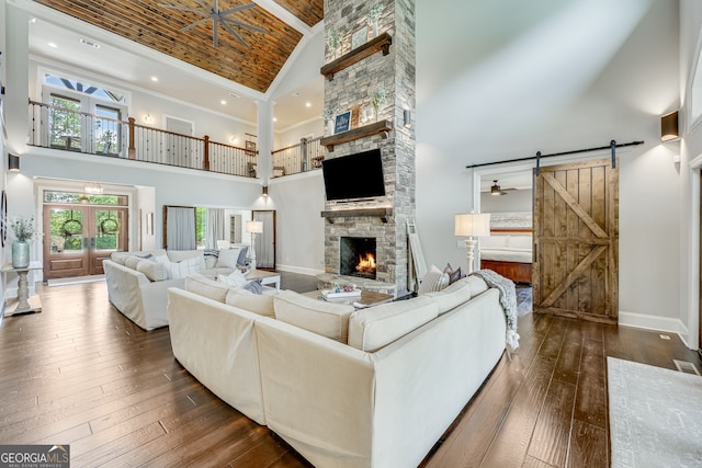 6590 Lights Ferry Rd, Flowery Branch, GA 30542 - living area featuring high vaulted ceiling, a stone fireplace, a barn door, and dark wood finished floors