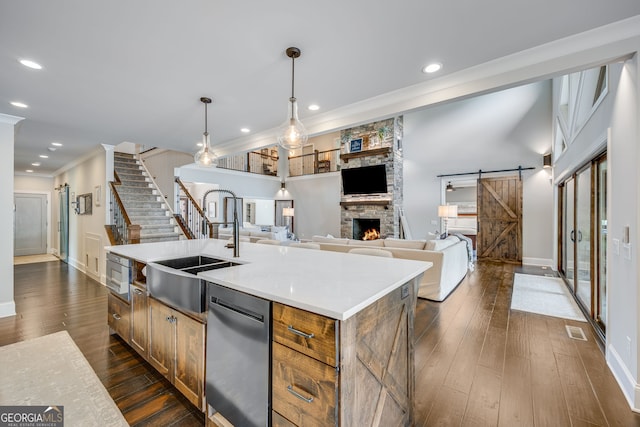 6590 Lights Ferry Rd, Flowery Branch, GA 30542 - kitchen with stainless steel appliances, a barn door, a center island with sink, dark wood-style floors, and ornamental molding