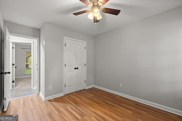 615 Coan Dr, Locust Grove, GA 30248 - unfurnished bedroom with light wood-style flooring, a closet, ceiling fan, and a textured ceiling