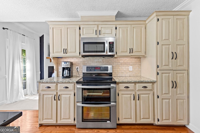 100 Merrill Dr, Lagrange, GA 30241 - kitchen with appliances with stainless steel finishes, cream cabinetry, crown molding, tasteful backsplash, and a textured ceiling