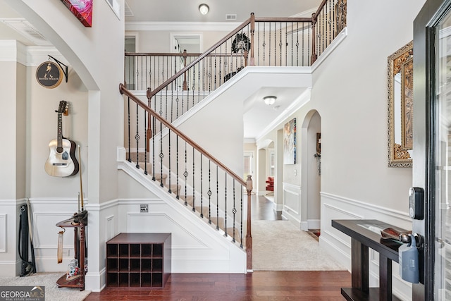3024 Bridgehaven Ct, Snellville, GA 30039 - stairs with a decorative wall, wood finished floors, a towering ceiling, ornamental molding, and a wainscoted wall