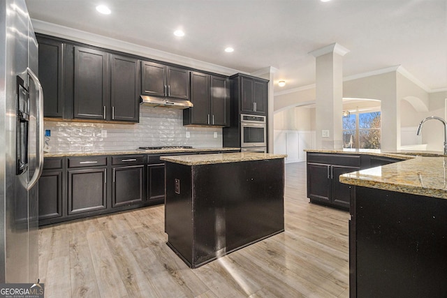 7691 Brazos Trl, Fairburn, GA 30213 - kitchen featuring stainless steel appliances, crown molding, arched walkways, light stone countertops, and light wood finished floors