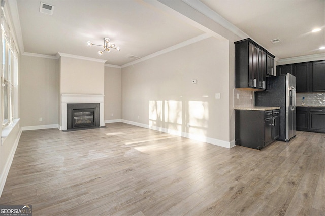 7691 Brazos Trl, Fairburn, GA 30213 - unfurnished living room featuring light wood finished floors, crown molding, a fireplace with flush hearth, and a chandelier