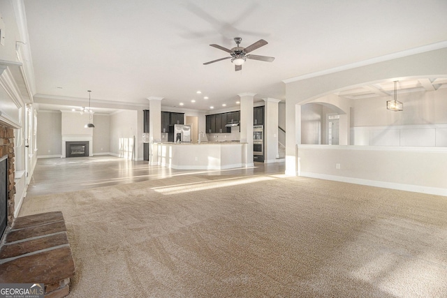 7691 Brazos Trl, Fairburn, GA 30213 - unfurnished living room featuring a glass covered fireplace, crown molding, light carpet, ceiling fan, and arched walkways