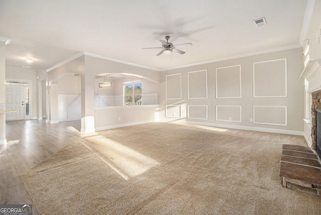 7691 Brazos Trl, Fairburn, GA 30213 - unfurnished living room featuring ceiling fan, crown molding, a fireplace, and arched walkways