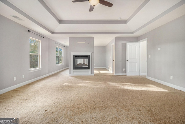 7691 Brazos Trl, Fairburn, GA 30213 - unfurnished living room featuring a tray ceiling, a multi sided fireplace, carpet, and ceiling fan