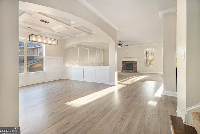 7691 Brazos Trl, Fairburn, GA 30213 - unfurnished living room featuring ceiling fan, a glass covered fireplace, ornamental molding, a chandelier, and wood finished floors