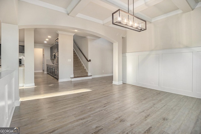 7691 Brazos Trl, Fairburn, GA 30213 - unfurnished dining area featuring a decorative wall, beam ceiling, arched walkways, stairs, and coffered ceiling