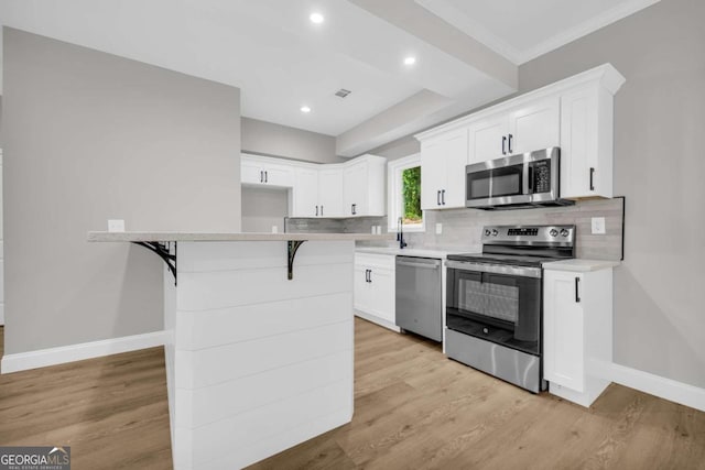 155 Carey St, Franklin Springs, GA 30662 - kitchen with appliances with stainless steel finishes, white cabinets, decorative backsplash, a kitchen breakfast bar, and recessed lighting