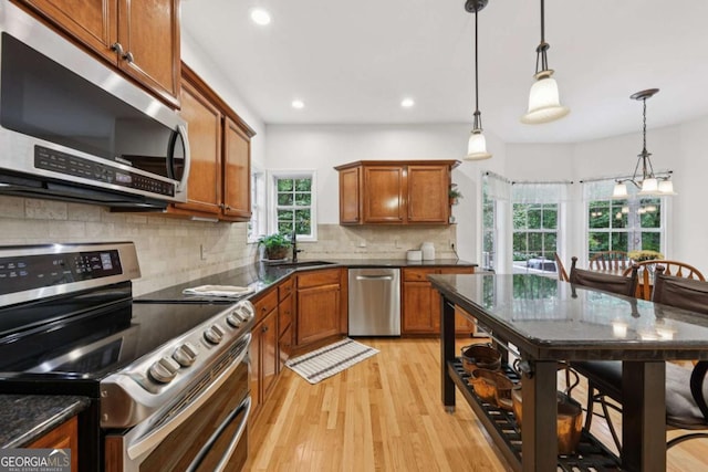 8485 Anchor On Lanier Ct, Gainesville, GA 30506 - kitchen featuring appliances with stainless steel finishes, light wood-style floors, brown cabinetry, decorative light fixtures, and decorative backsplash