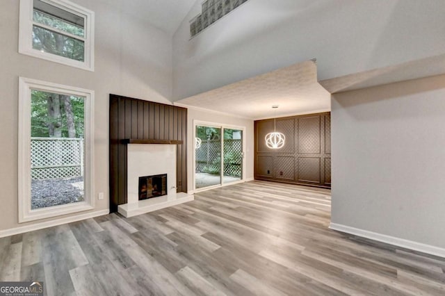 6221 Willow Run Rd, Peachtree Corners, GA 30092 - unfurnished living room with light wood-style floors, a large fireplace, and a towering ceiling
