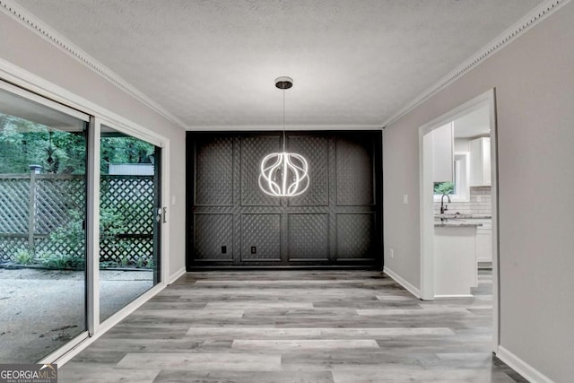 6221 Willow Run Rd, Peachtree Corners, GA 30092 - unfurnished dining area featuring light wood-style flooring, a chandelier, ornamental molding, and a textured ceiling