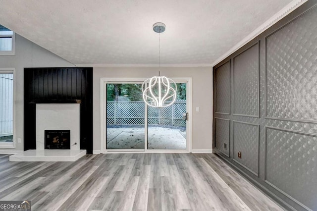 6221 Willow Run Rd, Peachtree Corners, GA 30092 - unfurnished dining area with a chandelier, light wood finished floors, plenty of natural light, a large fireplace, and ornamental molding