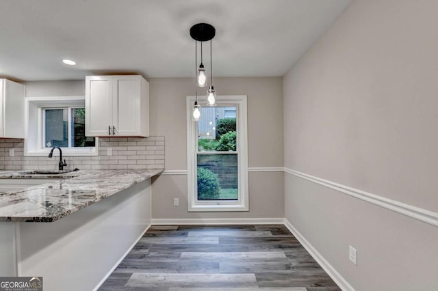 6221 Willow Run Rd, Peachtree Corners, GA 30092 - kitchen featuring white cabinets, tasteful backsplash, light stone counters, wood finished floors, and pendant lighting