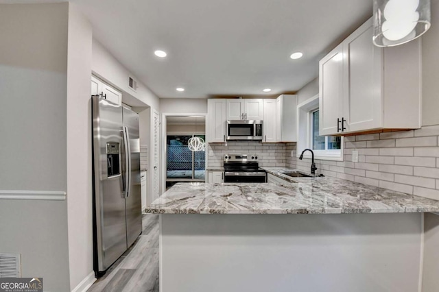 6221 Willow Run Rd, Peachtree Corners, GA 30092 - kitchen with appliances with stainless steel finishes, backsplash, a peninsula, white cabinetry, and light stone counters