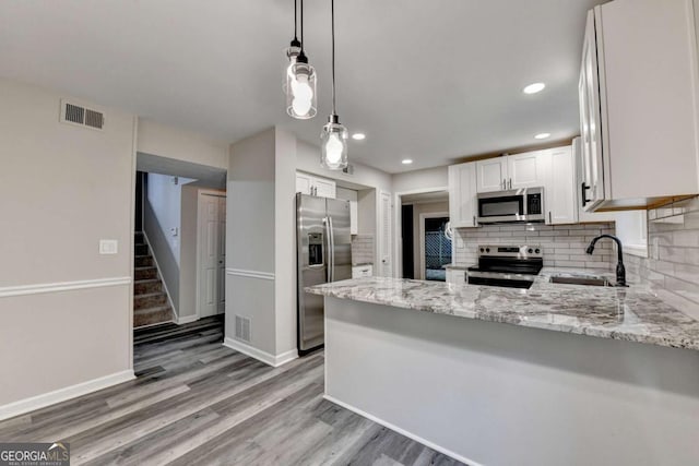 6221 Willow Run Rd, Peachtree Corners, GA 30092 - kitchen with stainless steel appliances, light stone countertops, decorative backsplash, a peninsula, and white cabinetry
