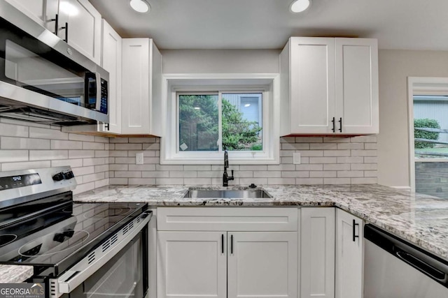 6221 Willow Run Rd, Peachtree Corners, GA 30092 - kitchen featuring appliances with stainless steel finishes, white cabinets, decorative backsplash, light stone counters, and recessed lighting