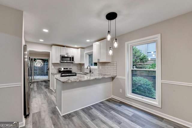 6221 Willow Run Rd, Peachtree Corners, GA 30092 - kitchen featuring appliances with stainless steel finishes, white cabinets, a peninsula, tasteful backsplash, and light wood-style flooring