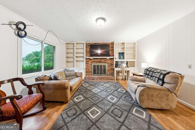 155 Windy Hill Ct, Alpharetta, GA 30004 - living room with wood finished floors, a textured ceiling, a brick fireplace, and built in shelves