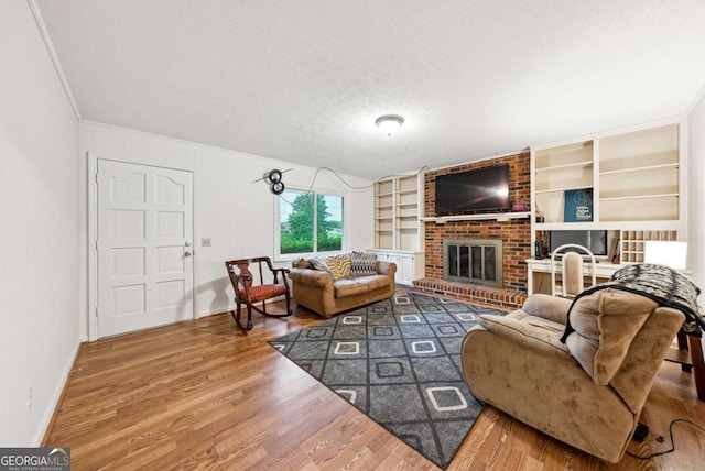 155 Windy Hill Ct, Alpharetta, GA 30004 - living room with wood finished floors, a fireplace, a textured ceiling, built in features, and crown molding