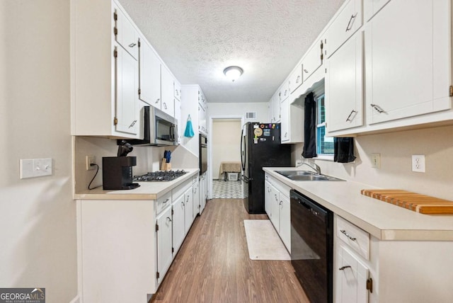 155 Windy Hill Ct, Alpharetta, GA 30004 - kitchen with black appliances, wood finished floors, light countertops, white cabinets, and a textured ceiling