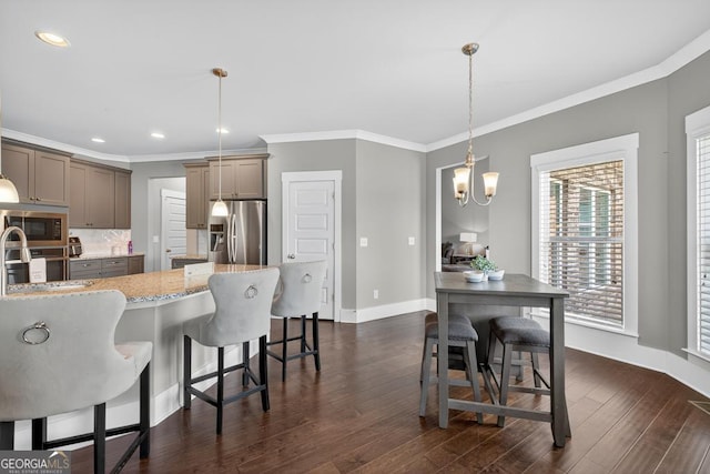 2112 Meadowood Cv, Monroe, GA 30655 - kitchen with appliances with stainless steel finishes, a breakfast bar area, light stone countertops, ornamental molding, and dark wood-style floors