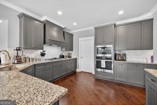 2112 Meadowood Cv, Monroe, GA 30655 - kitchen featuring stainless steel appliances, premium range hood, gray cabinetry, light stone countertops, and tasteful backsplash