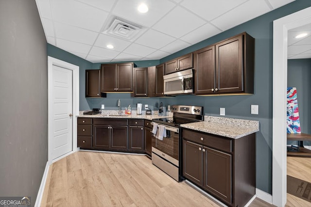 2112 Meadowood Cv, Monroe, GA 30655 - kitchen with stainless steel appliances, a paneled ceiling, light wood-style flooring, dark brown cabinetry, and light stone countertops