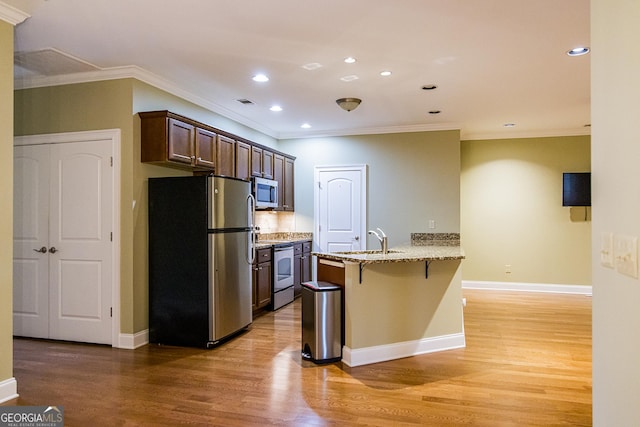 105 Maplecrest Ln SE, Rome, GA 30161 - kitchen with stainless steel appliances, a breakfast bar area, light wood-style floors, ornamental molding, and light stone countertops