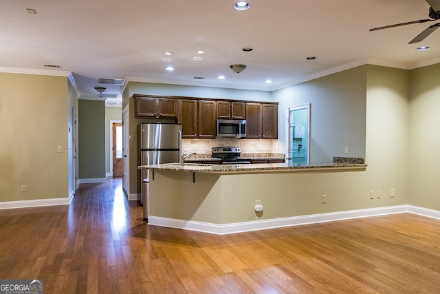 105 Maplecrest Ln SE, Rome, GA 30161 - kitchen featuring stainless steel appliances, wood finished floors, light stone countertops, dark brown cabinetry, and ceiling fan