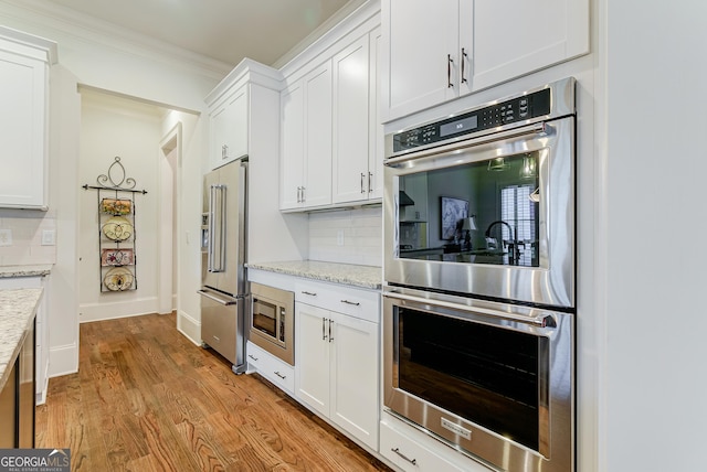 1911 Bent Pine Park, Statham, GA 30666 - kitchen with appliances with stainless steel finishes, tasteful backsplash, white cabinetry, light wood-style flooring, and crown molding
