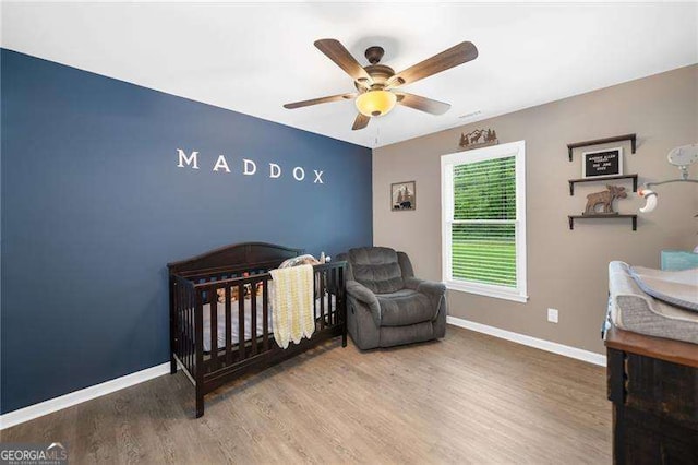 154 Fairview Rd, Ball Ground, GA 30107 - bedroom featuring wood finished floors, a nursery area, and ceiling fan